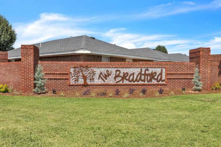 The Bradford entrance sign on a brick wall with landscaping and green lawn