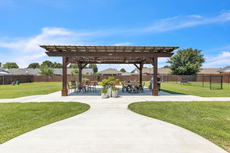 Outdoor pavilion with a grill area and seating, reached by a curved walkway