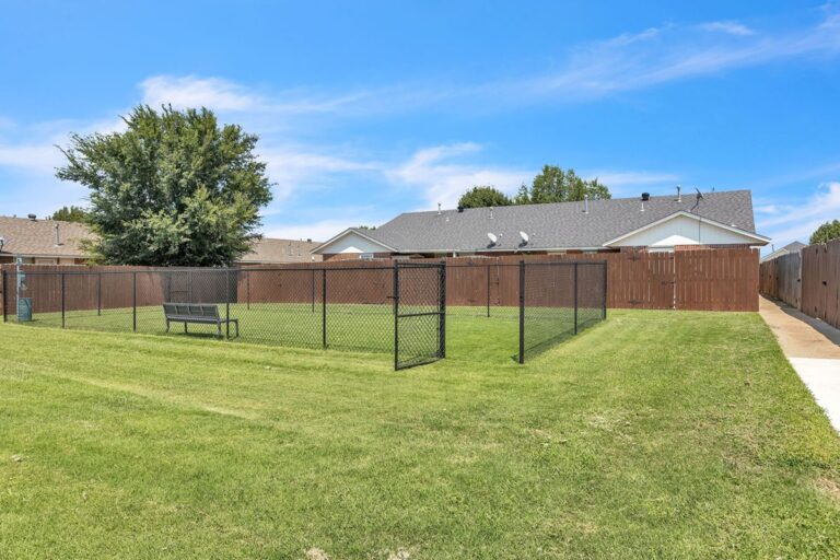 Fenced Bark Park with grass and a bench for residents and their pets