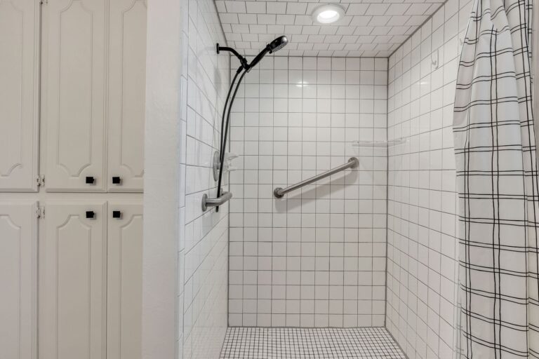 Cottage walk-in tiled shower with a grab bar and handheld shower head
